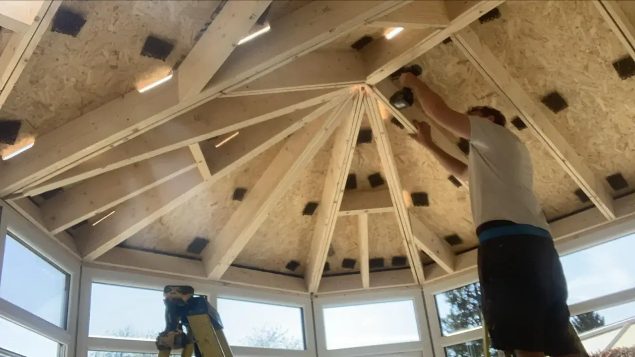 Installer constructing the internal timber framework for a conservatory warm roof conversion. By Norfolk Exterior Solutions.